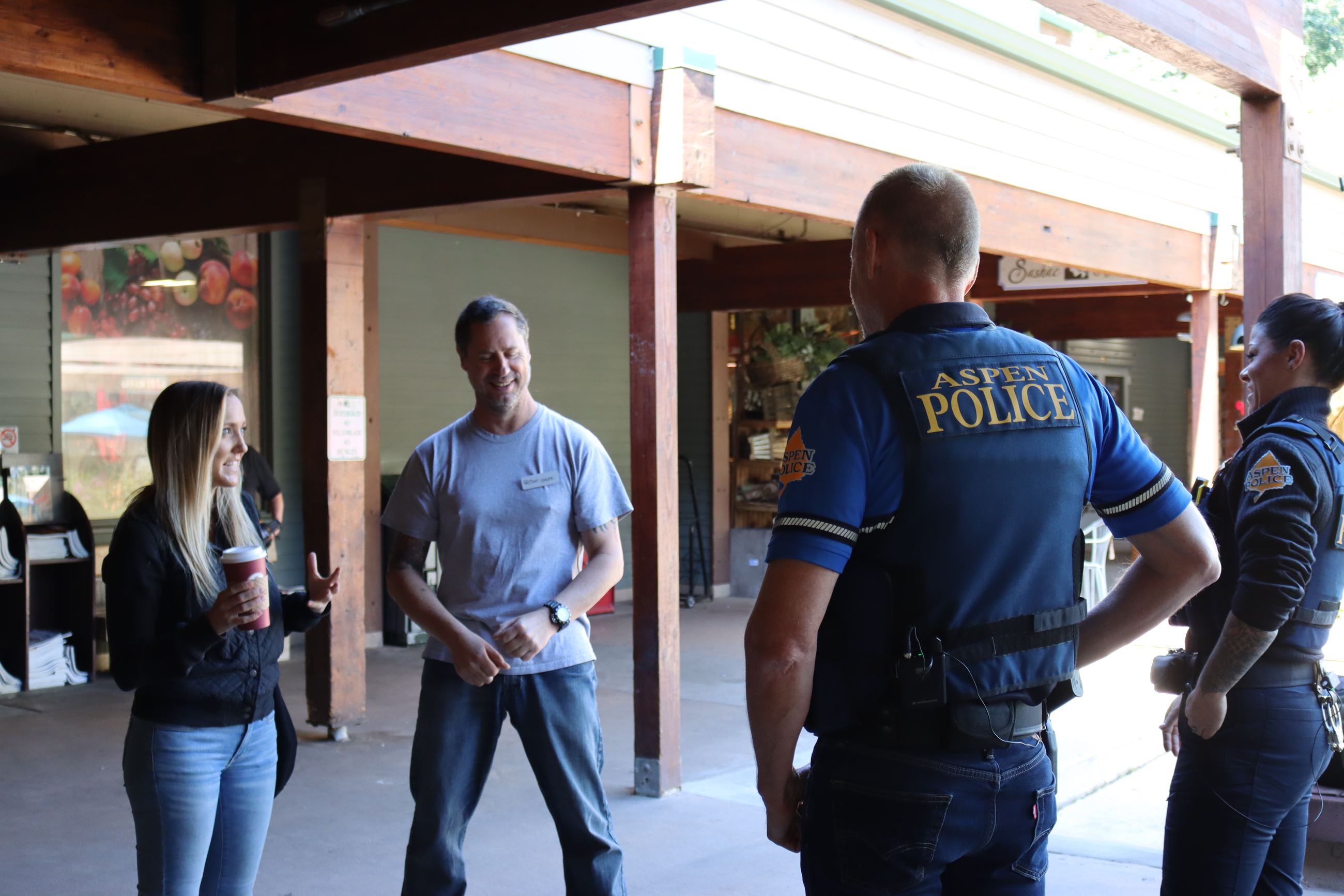 Male and female police officers in blue uniforms speaking to one male and one female citizen